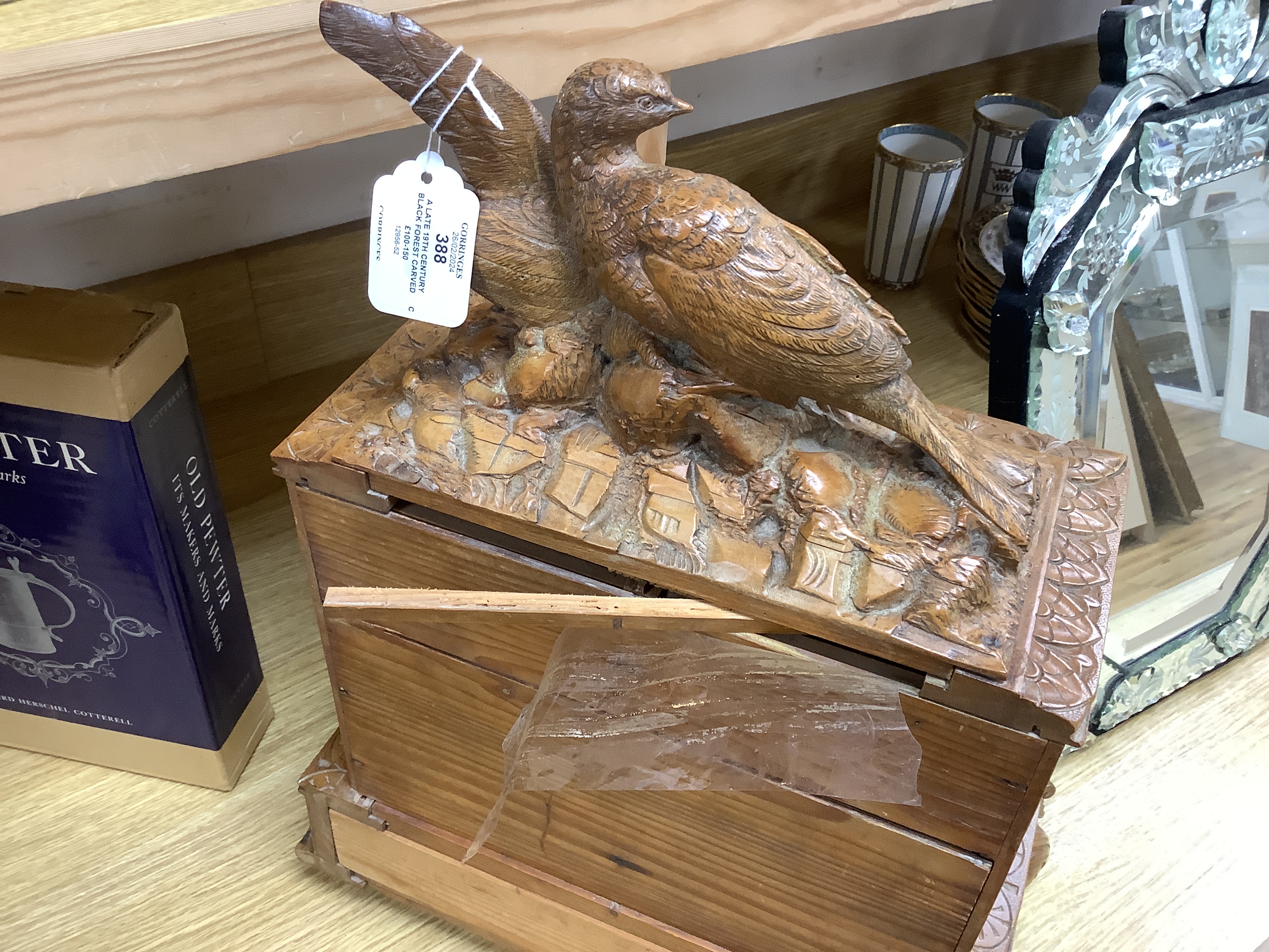A late 19th century Black Forest carved wooden two door table top cabinet, interior with fitted drawers, surmounted with two pheasants, 51cm high